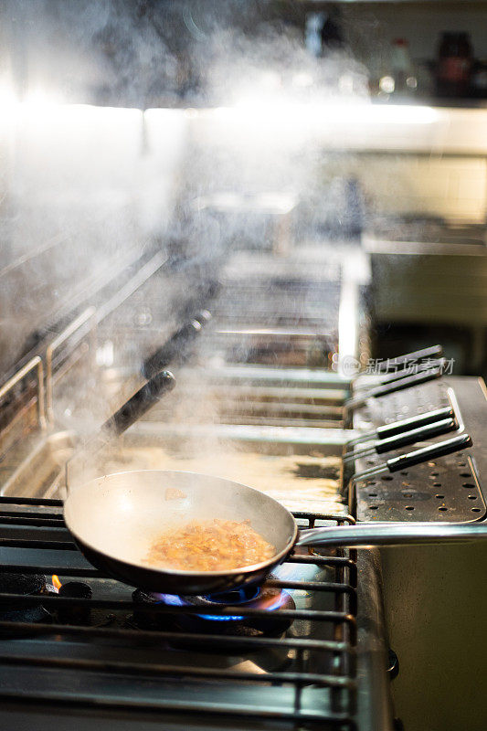 Action shot of chef cooking pasta in restaurant on frying pan